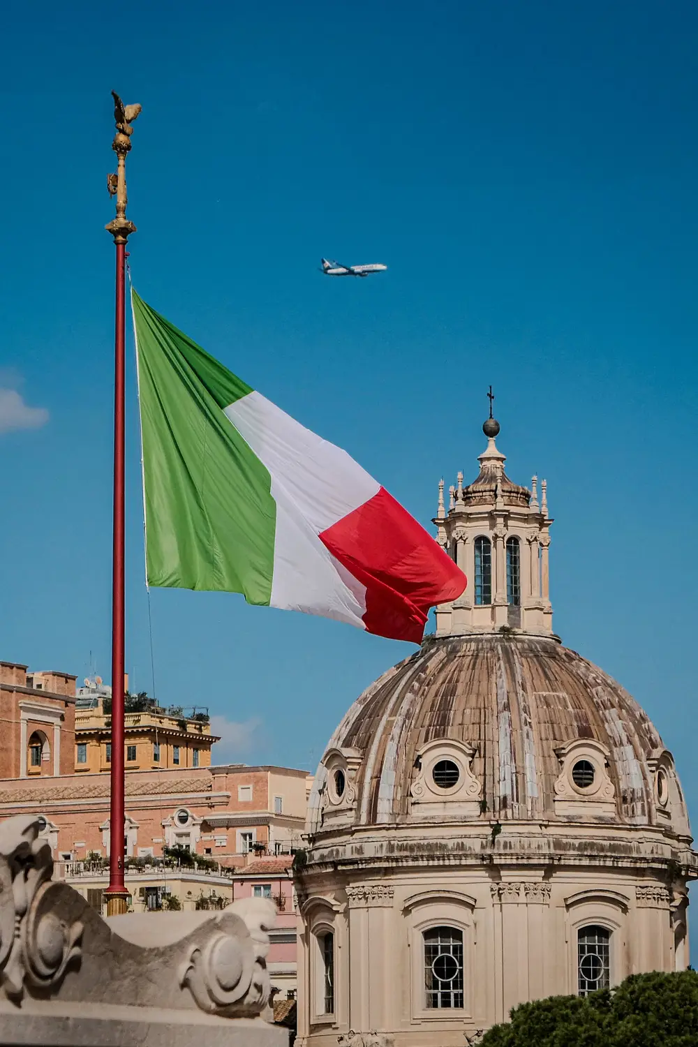 Italian flag flying above a domed church rooftop in Rome