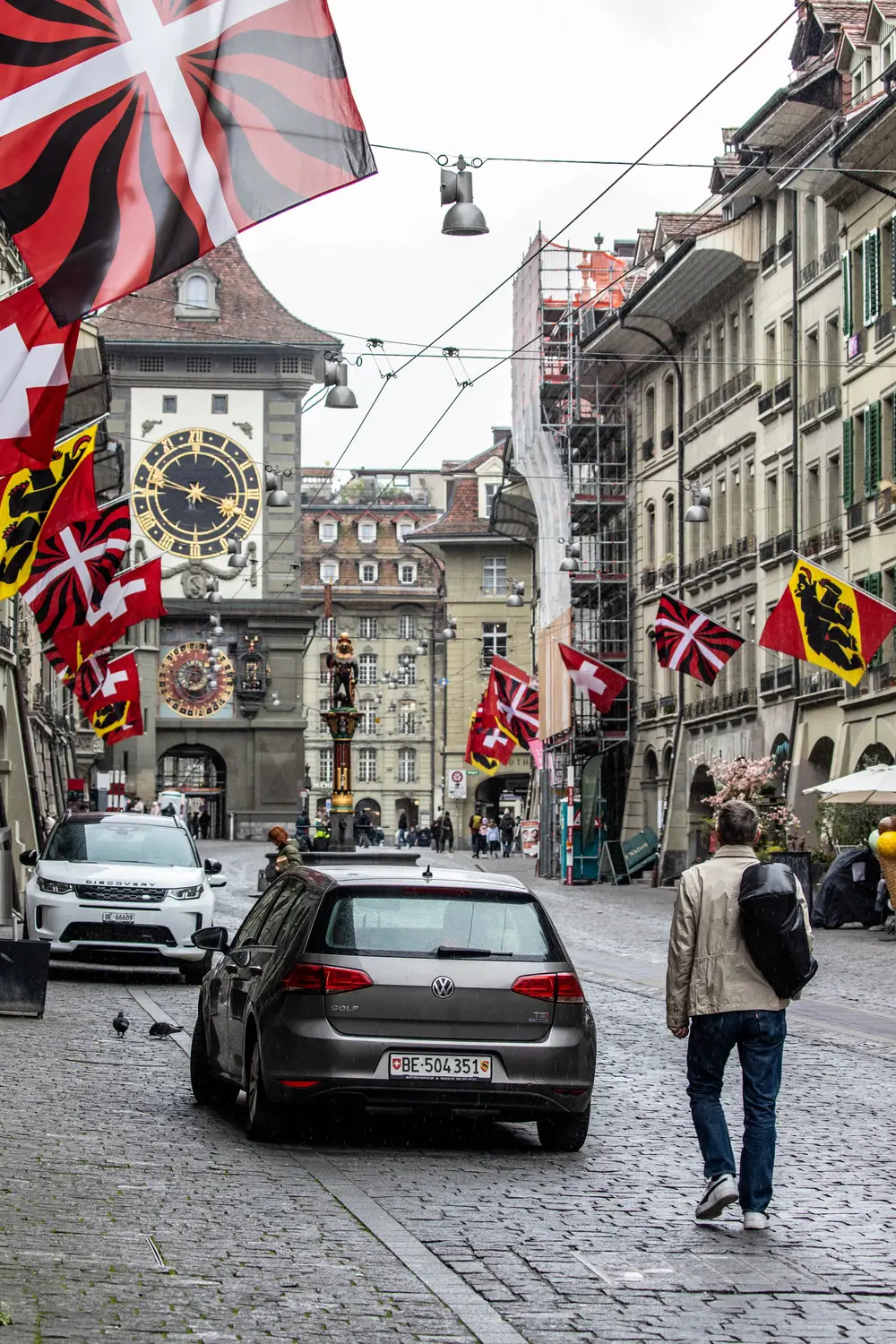 Historic clock tower and cobblestone street decorated with Swiss cantonal flags, Bern, Switzerland