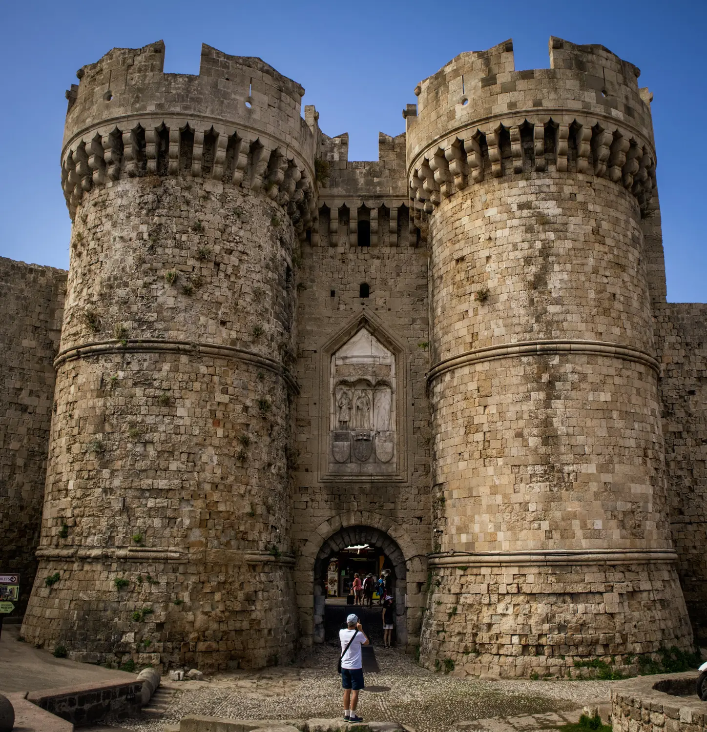 The medieval fortified gate of the Palace of the Grand Master in Rhodes, with two round stone towers flanking the entrance.
