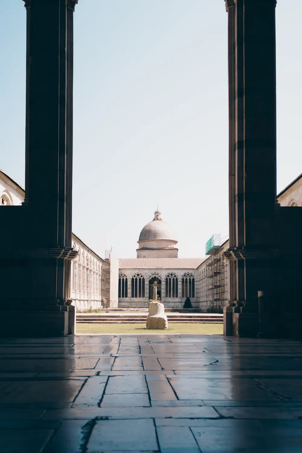 View through a colonnade toward a domed building in a Roman piazza