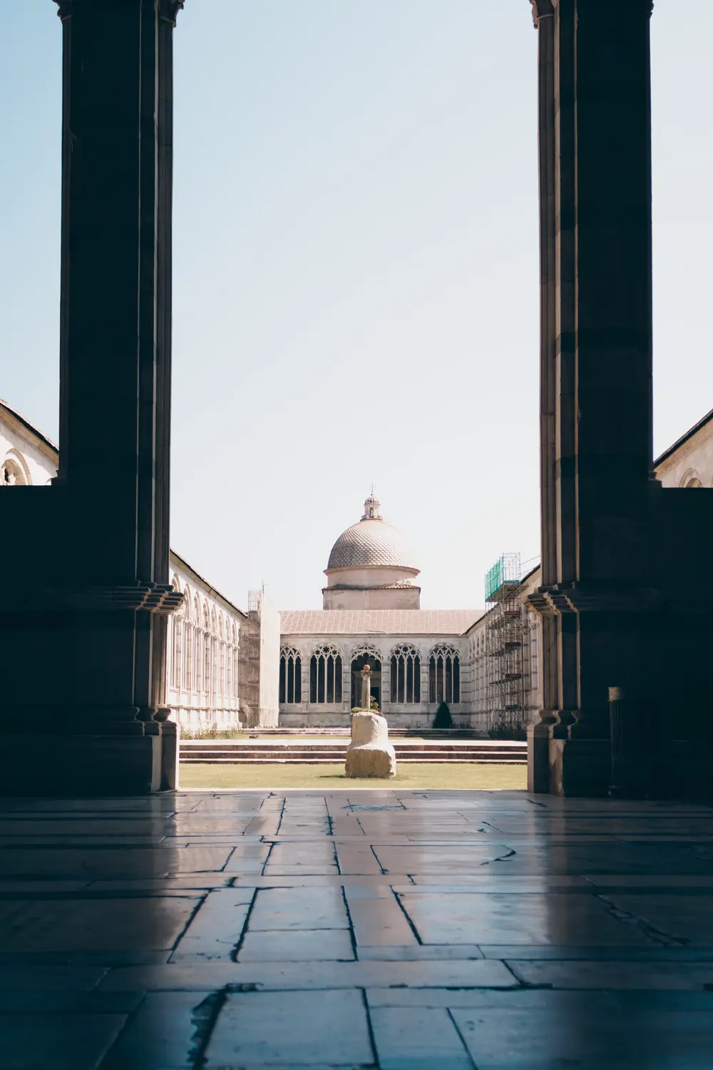 View through a colonnade toward a domed building in a Roman piazza