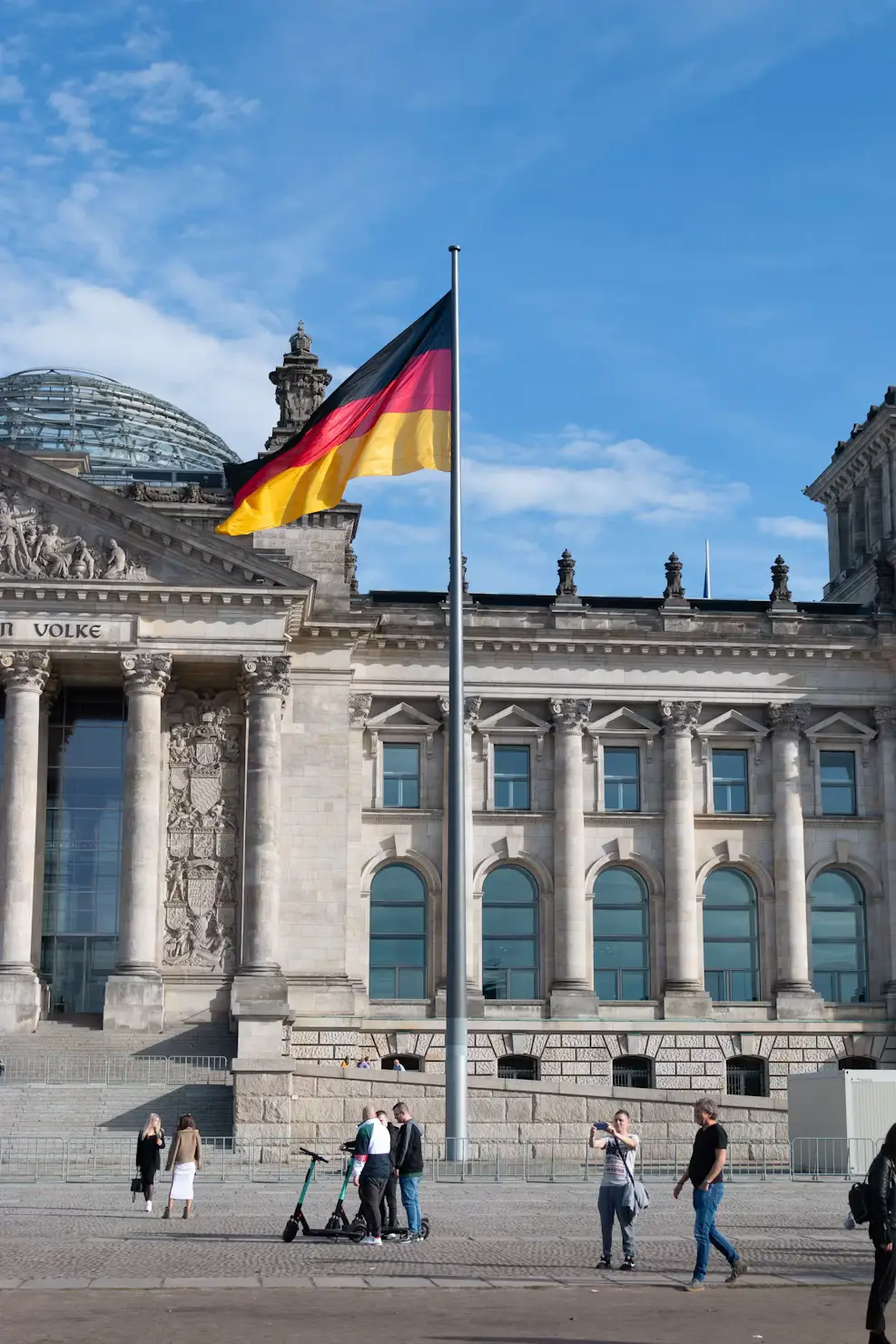 German flag flying in front of the Reichstag building with visitors below