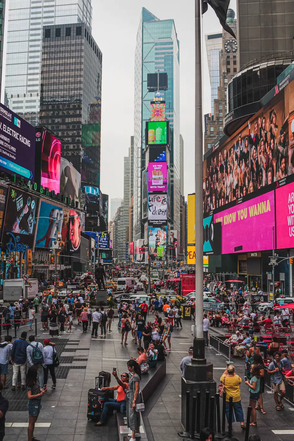 Crowds filling Times Square beneath towering buildings covered in bright neon billboards.