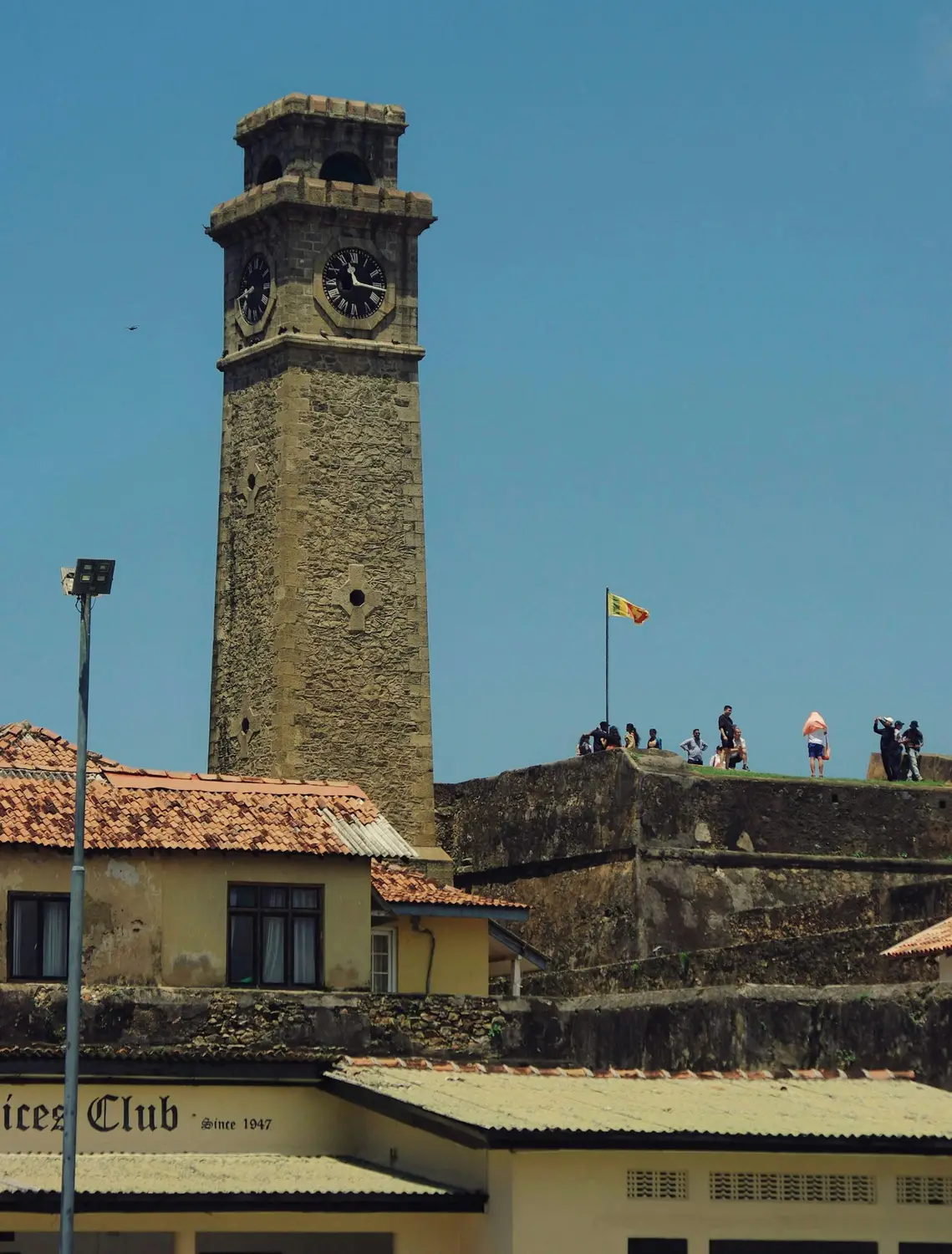 Old stone clock tower rising above the ramparts and rooftops of the historic Galle Fort in Sri Lanka.