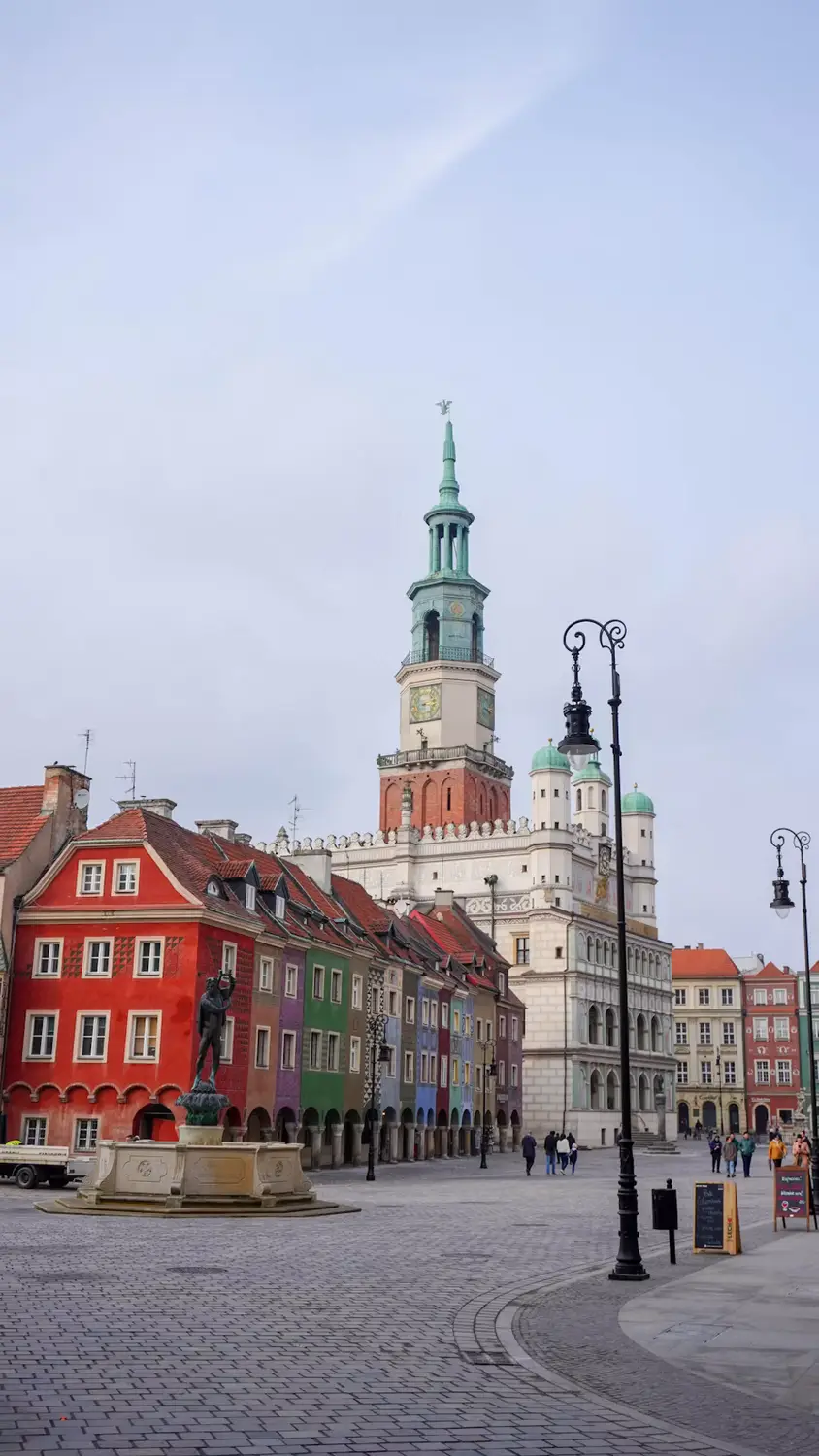 Historic European town square with colorful buildings and a prominent church tower.