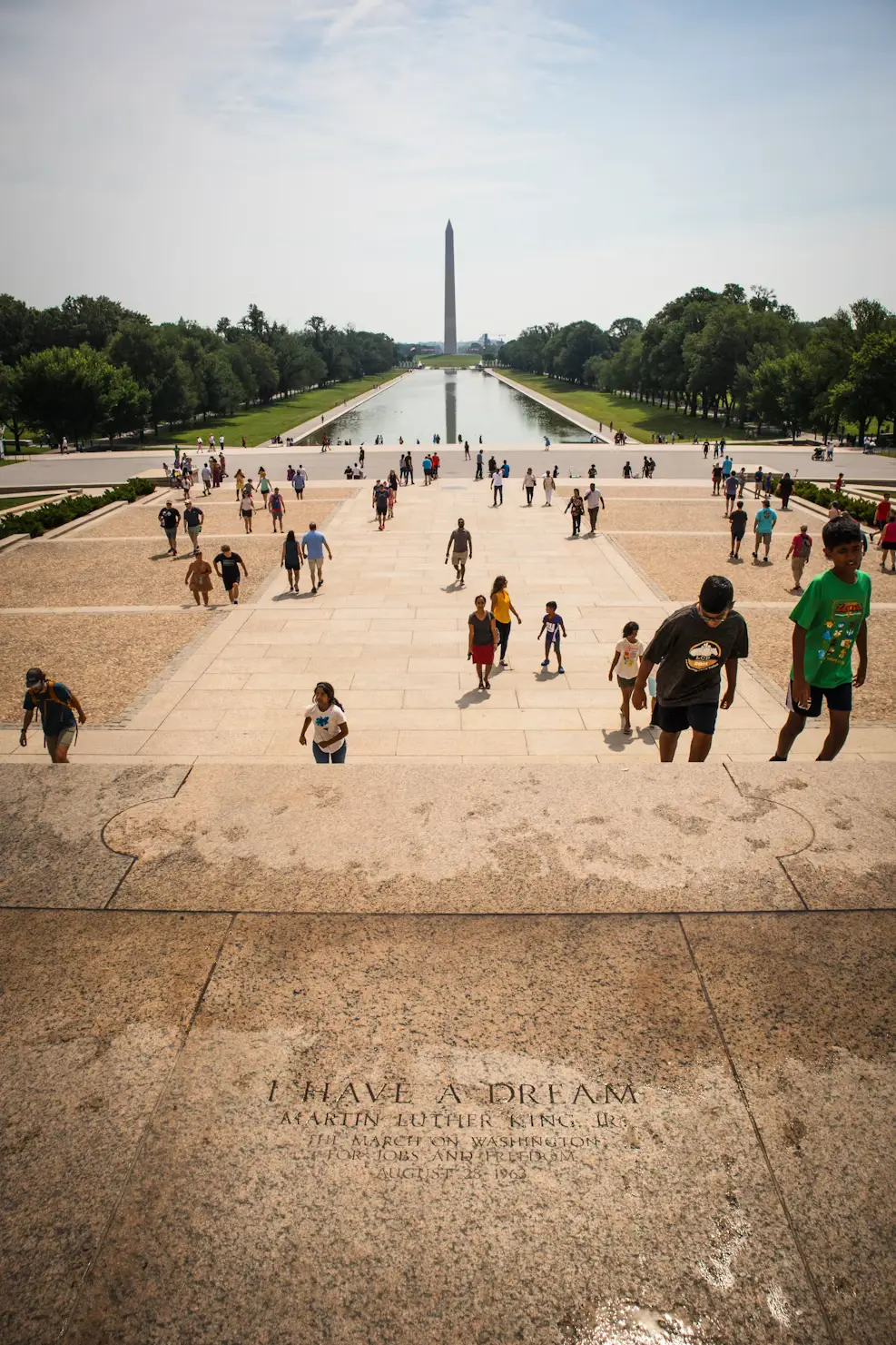 View from the Lincoln Memorial steps looking down the National Mall, with visitors walking toward the reflecting pool and Washington Monument
