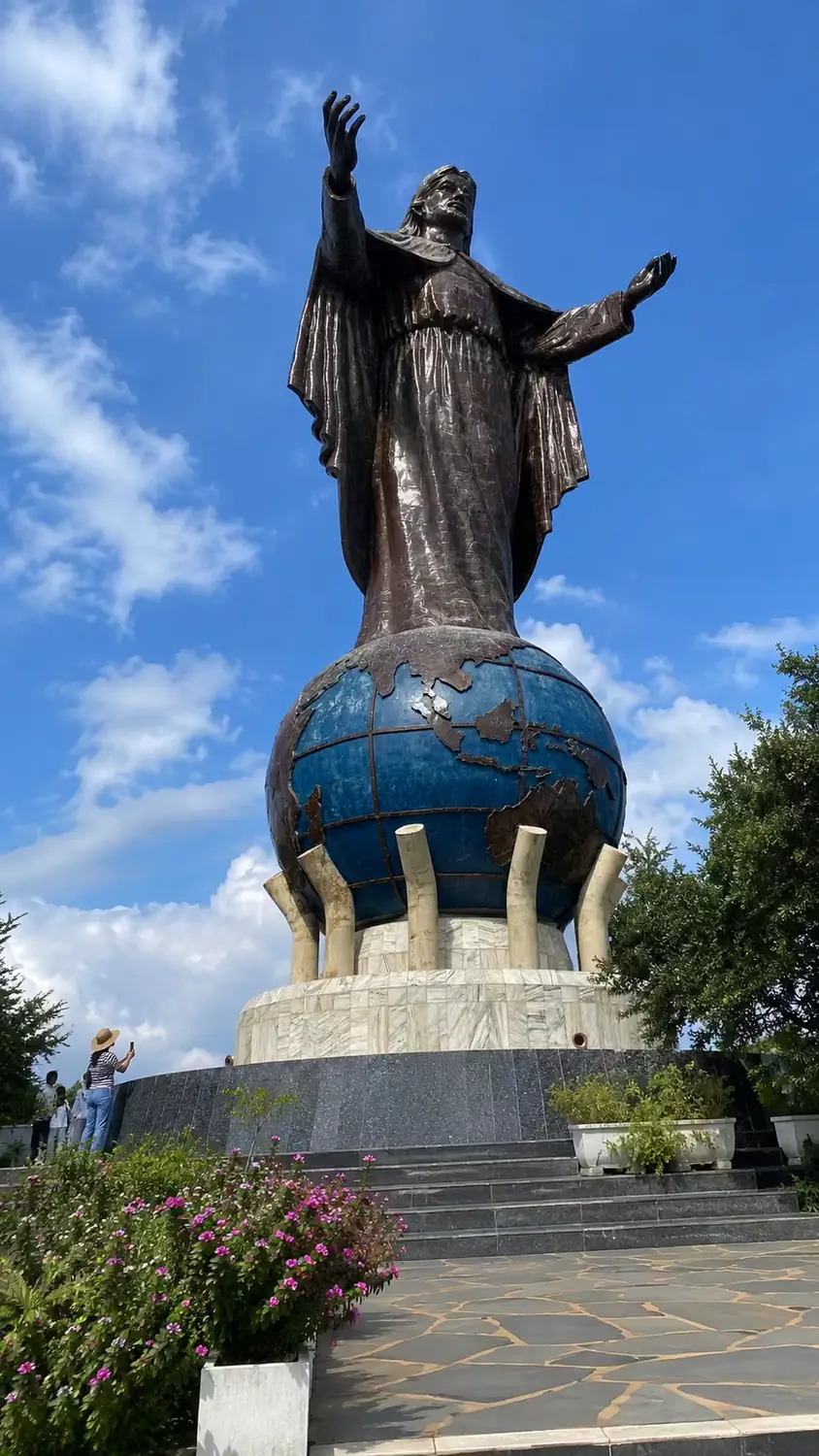 Cristo Rei statue in Dili, Timor-Leste – large bronze figure of Jesus Christ standing on a blue globe pedestal with arms raised, set against a blue sky
