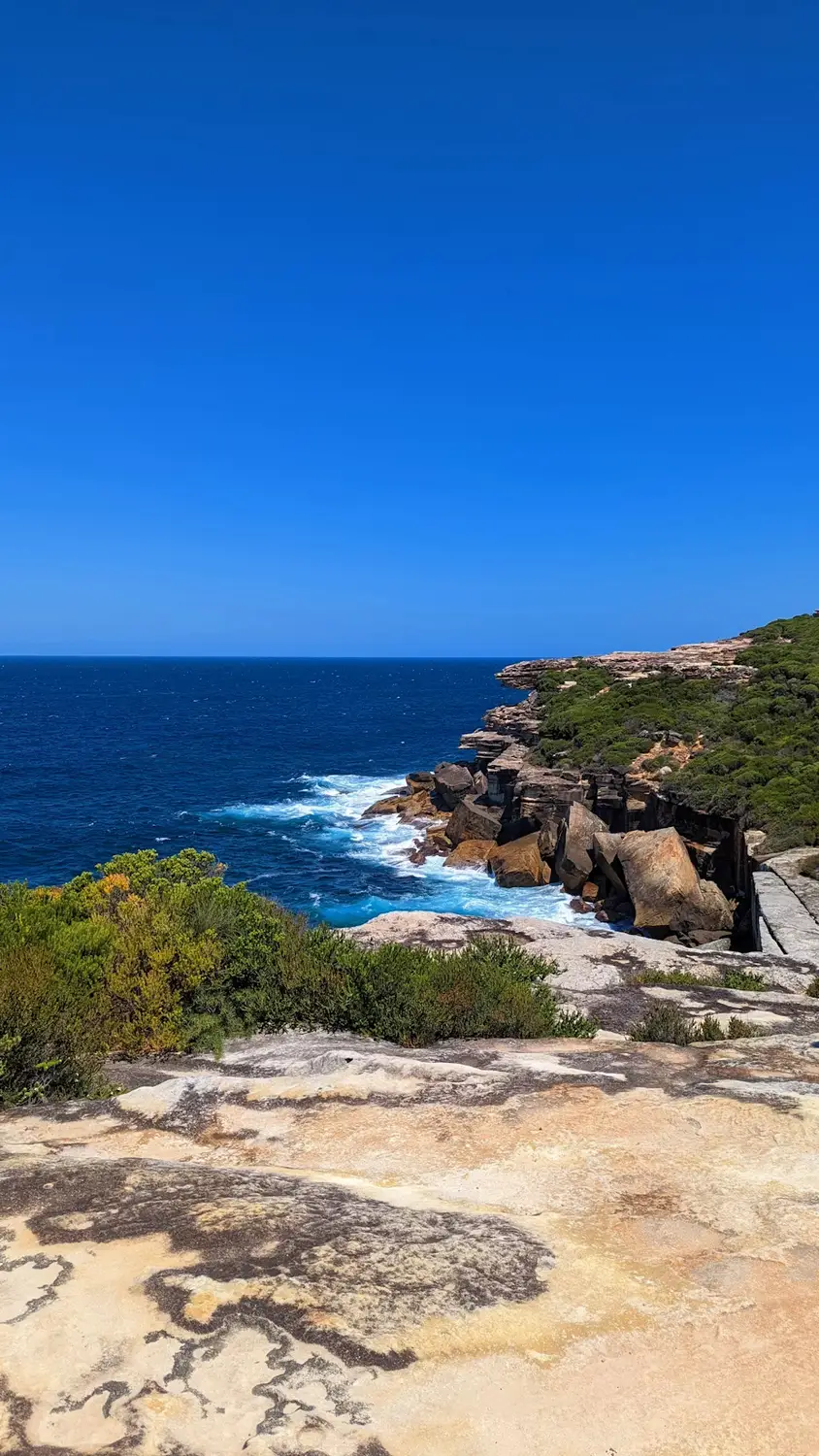 Rocky coastal headland with turquoise ocean and clear blue sky, Australia