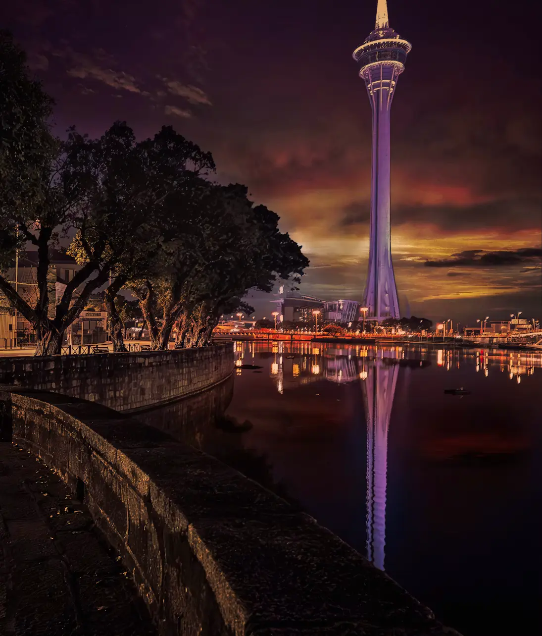 Macau Tower illuminated at dusk with waterfront reflection
