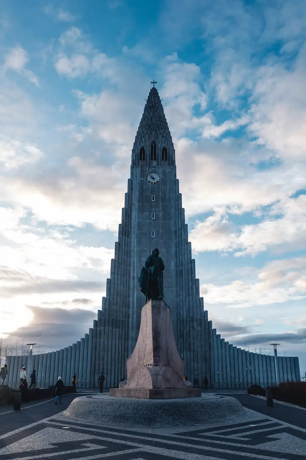 Statue of Leif Erikson standing before the tall, organ-pipe-like tower of Hallgrímskirkja church at dusk, Reykjavík, Iceland.