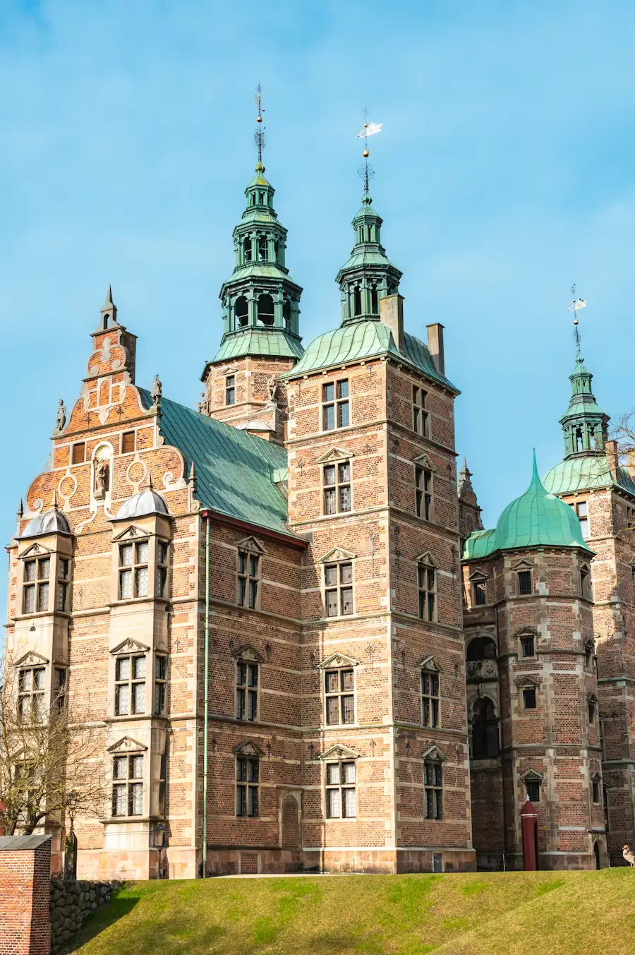 Rosenborg Castle in Copenhagen with its red-brick towers and green spires under a clear blue sky