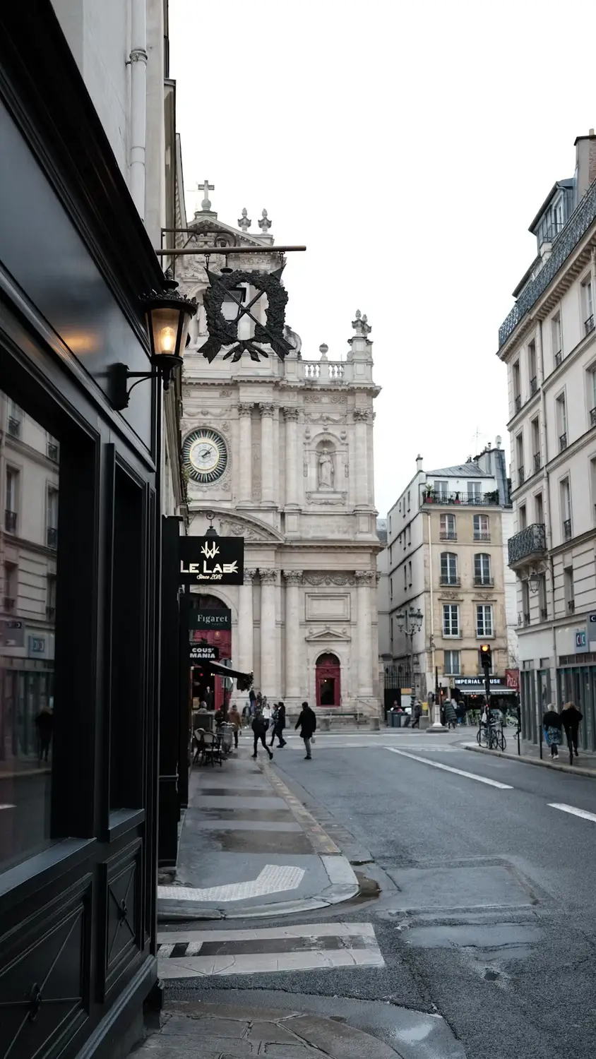 Quiet Parisian street corner with a classic clock tower and café storefront