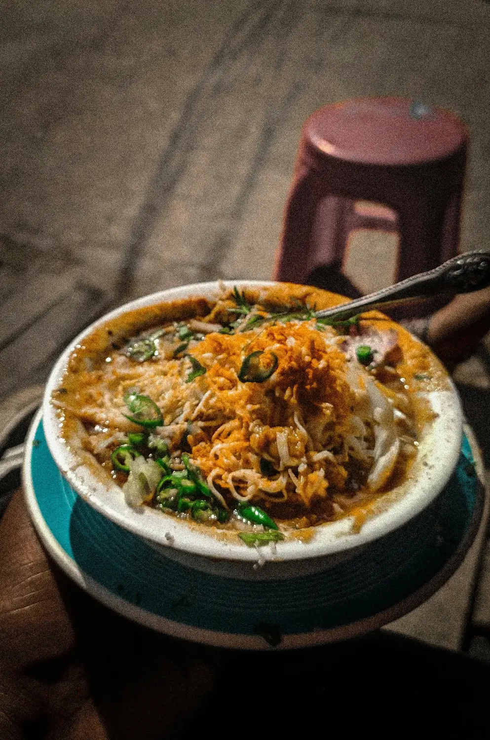 Mohinga Myanmar fish noodle soup topped with crispy fritters and green chilies served at a Yangon street food stall