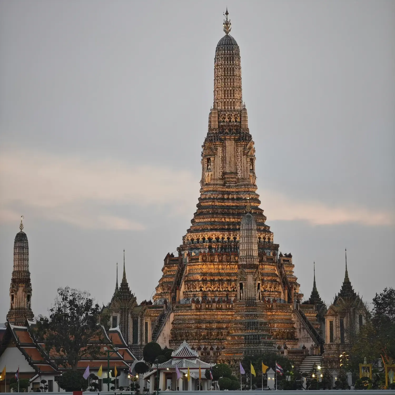 Wat Arun temple spire rising against a cloudy sky in Bangkok, Thailand