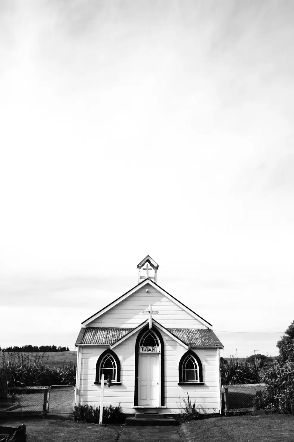 Small white church with black trim standing alone beneath a wide open sky.
