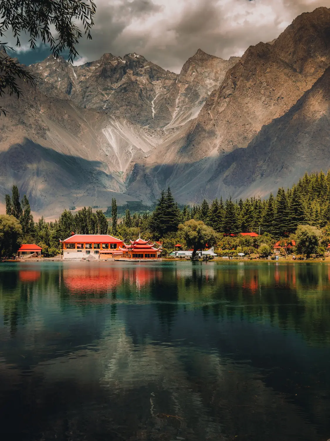 Lower Kachura Lake with red roofed resort reflecting in calm water and Karakoram mountains Skardu Pakistan