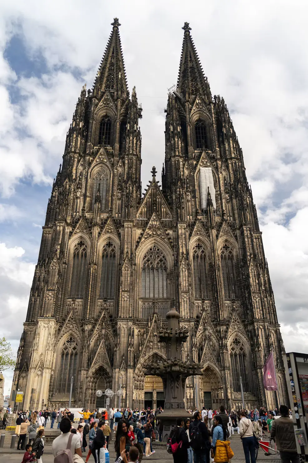 Close-up of Cologne Cathedral's Gothic facade and twin spires with crowds below