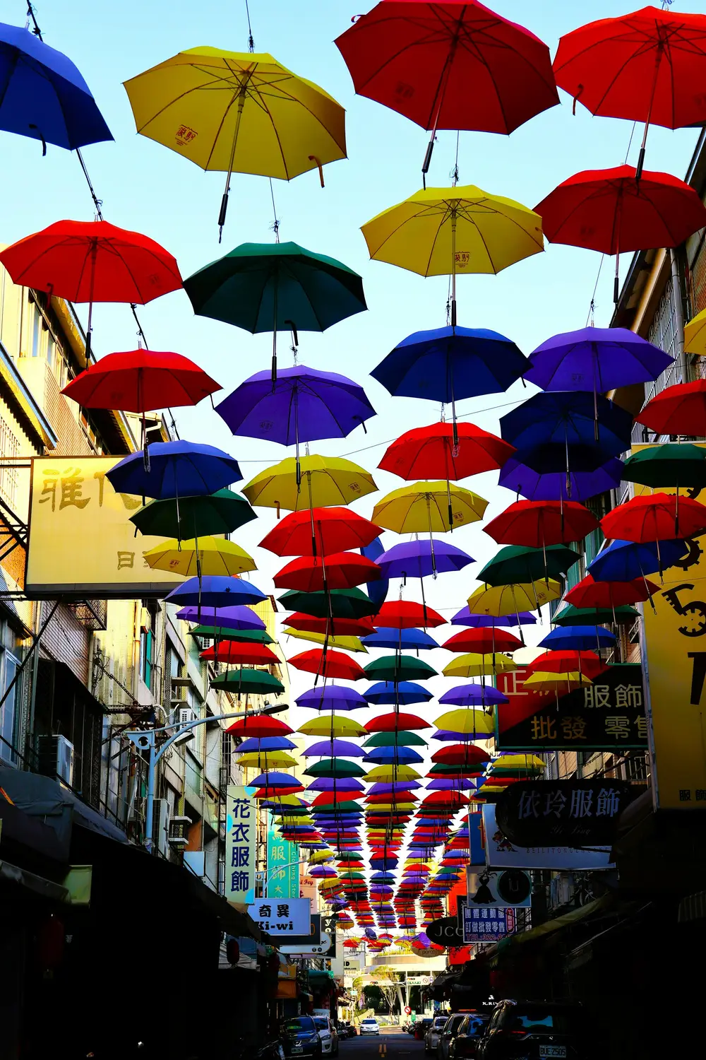 Canopy of brightly colored open umbrellas suspended over a narrow Taiwan shopping street