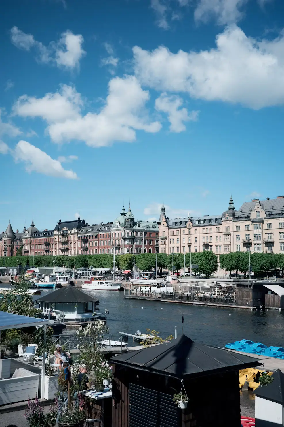 Waterfront view of Stockholm with boats moored along the quay and a row of grand buildings in the background.
