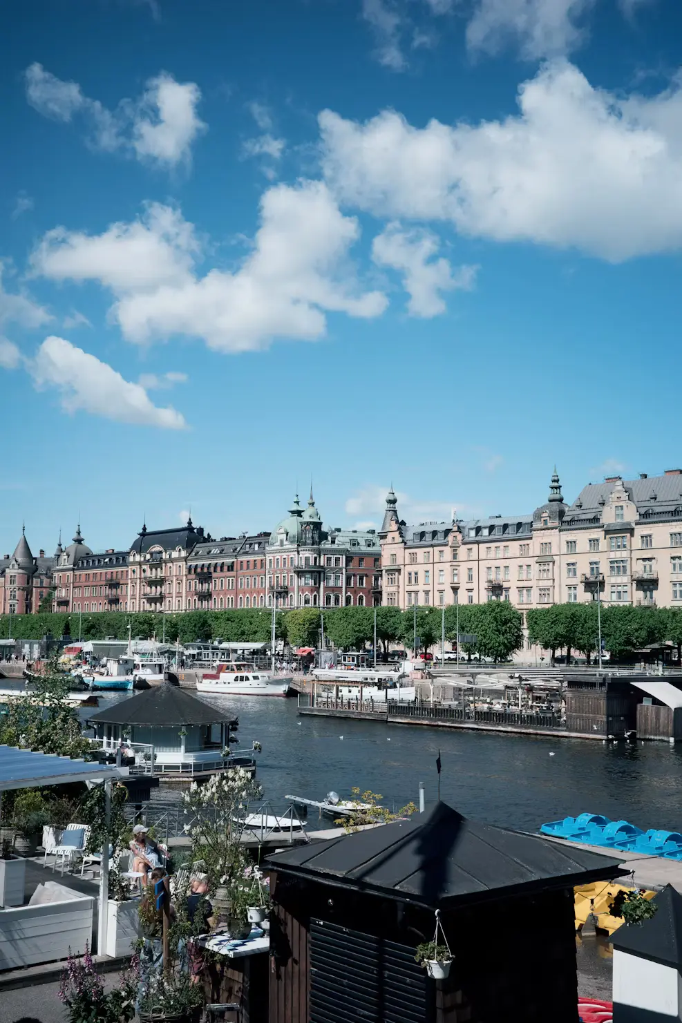 Waterfront view of Stockholm with boats moored along the quay and a row of grand buildings in the background.