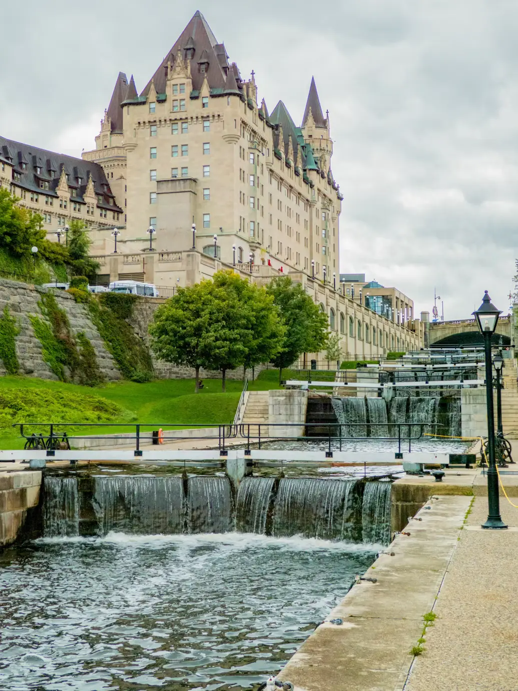 The historic Fairmont Château Laurier hotel beside a set of stone canal locks with cascading water.
