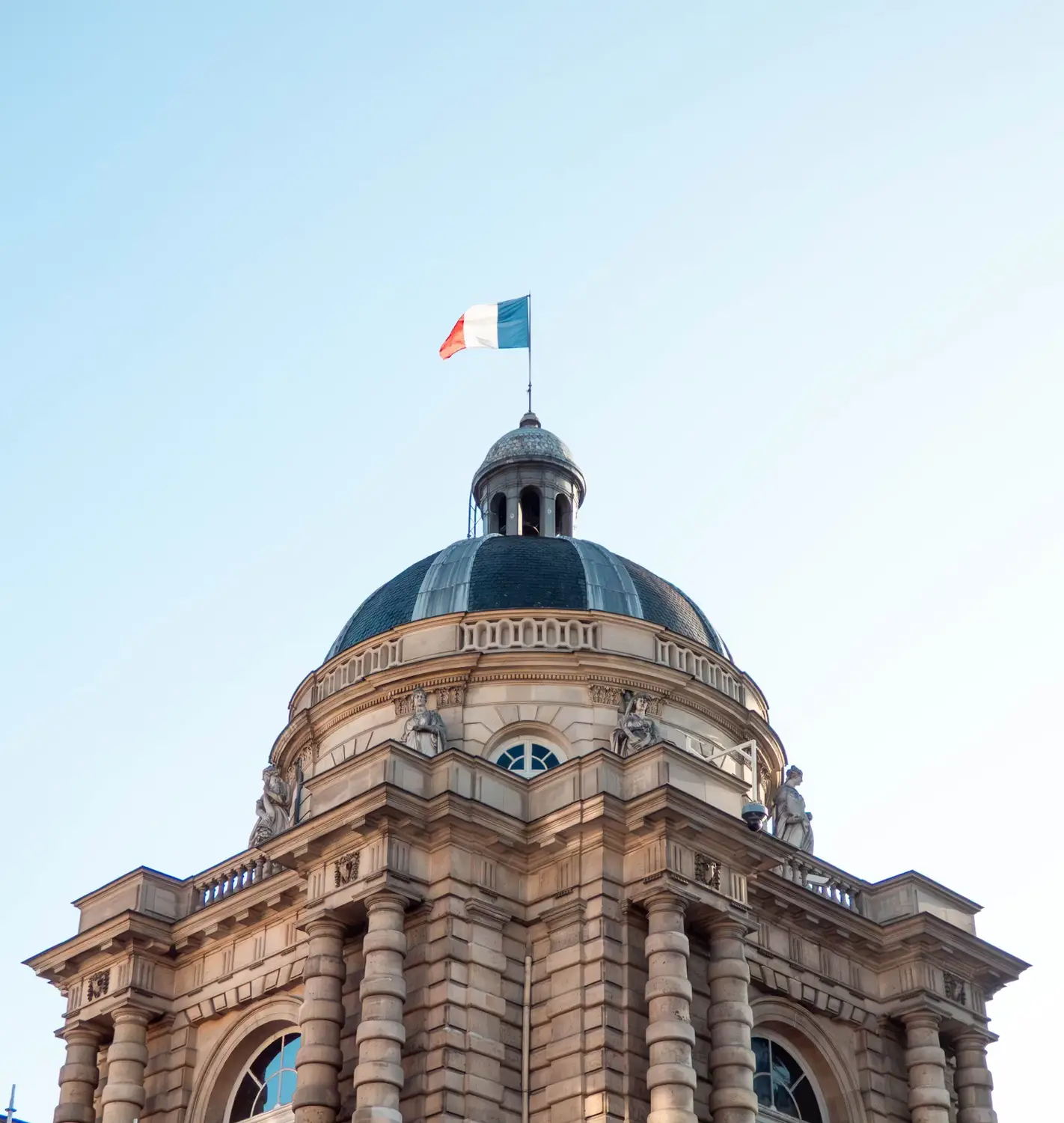 Sorbonne University dome with the French flag flying against a clear sky