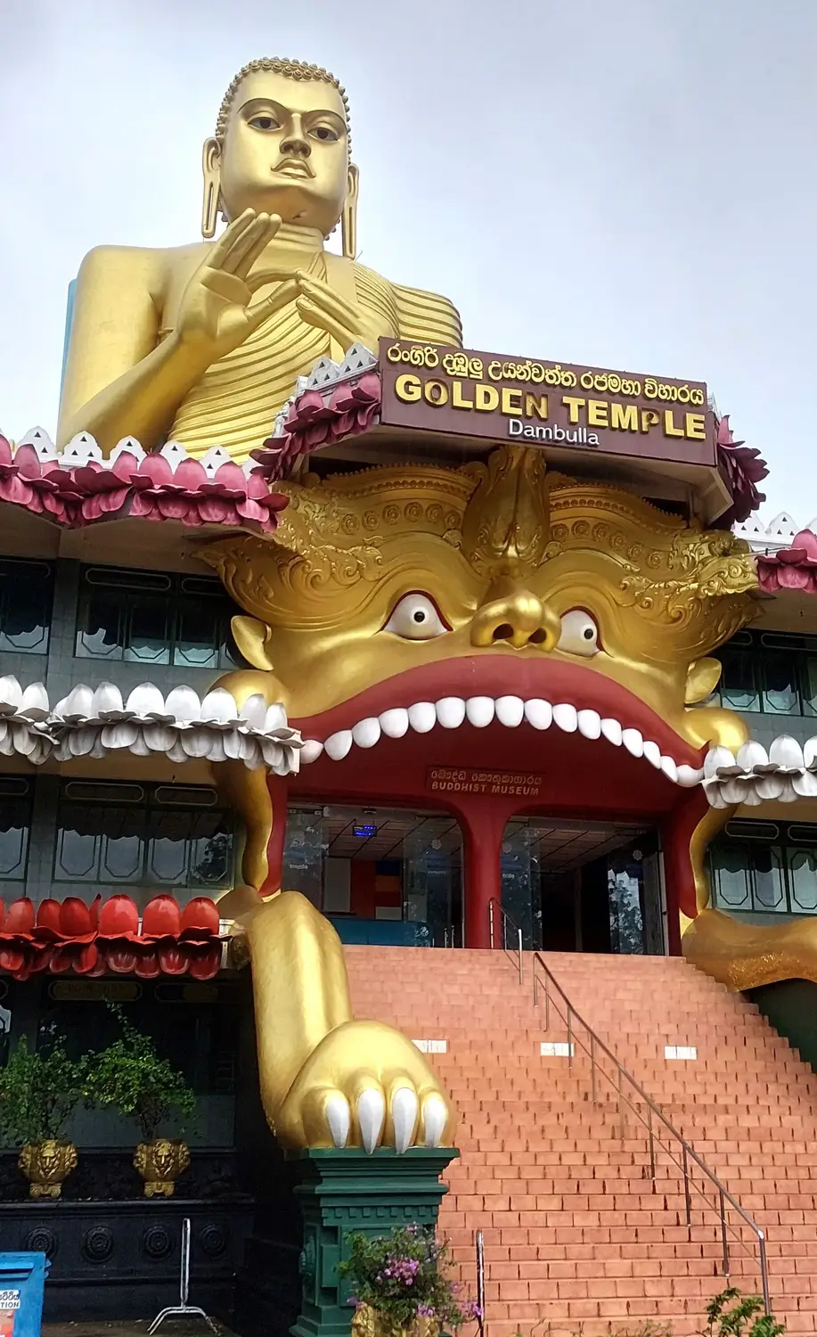 Golden Buddha statue atop the ornate entrance of the Golden Temple in Dambulla, Sri Lanka.