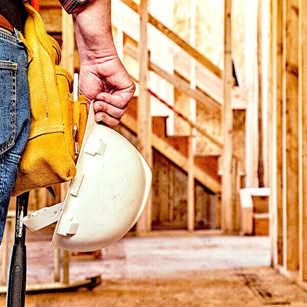 construction worker holding hardhat in wooden framed house