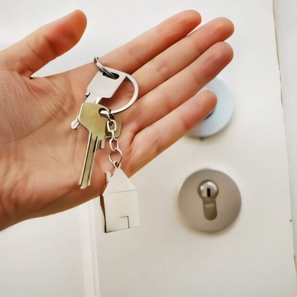 hand holding key chain in front of door lock