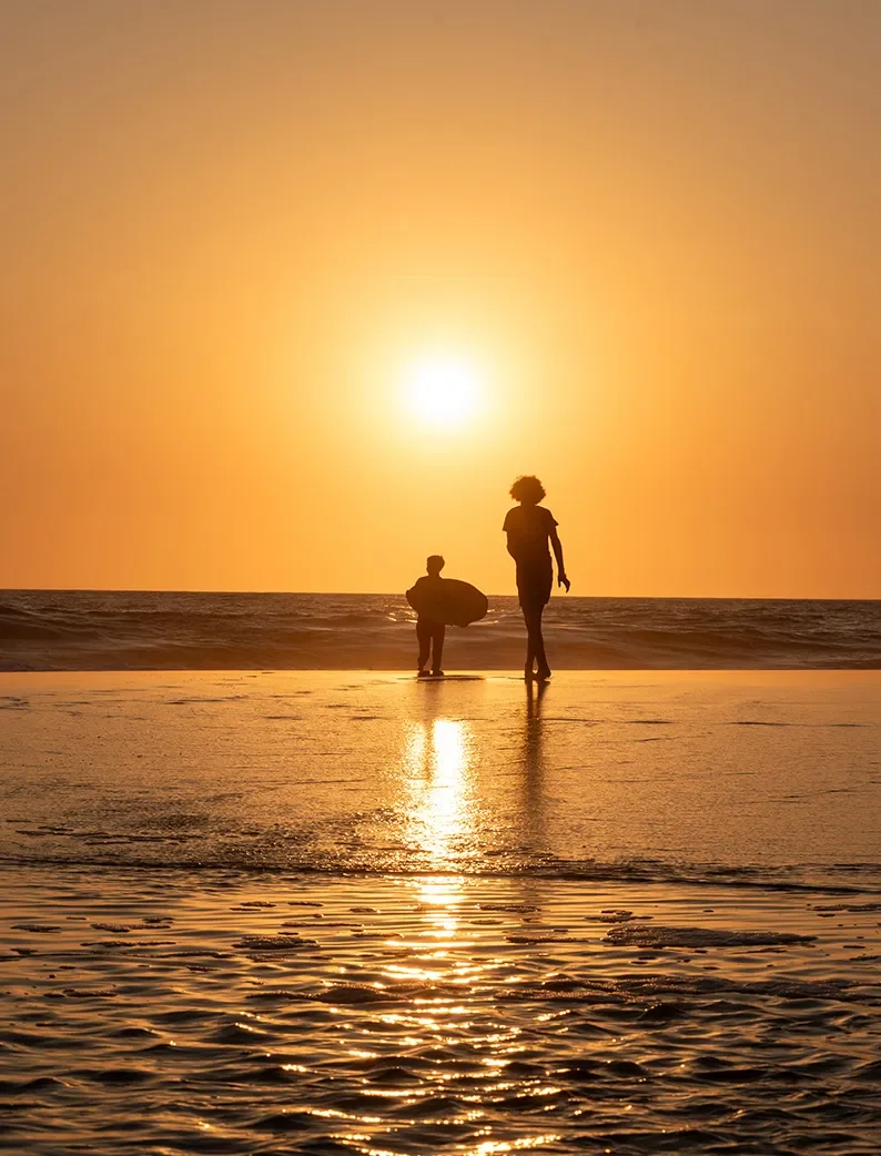 Adulte et enfant sur la plage du Vivier à Biscarrosse au coucher du soleil.