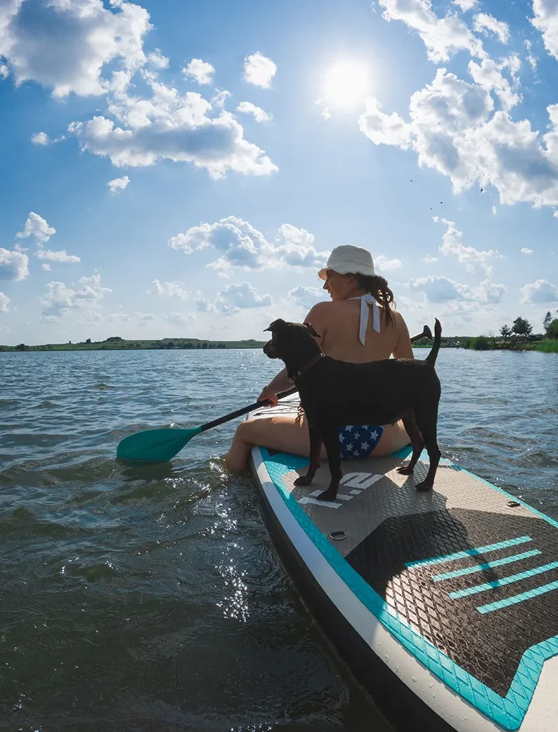 Une femme qui fait du paddle sur le lac de Biscarrosse avec un chien sur la planche.