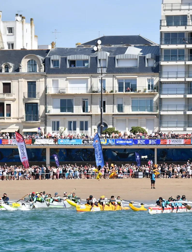 Départ de la Vendée Va'a, une course de pirogues aux Sables d'Olonne, avec de nombreux spectateurs en arrière-plan.