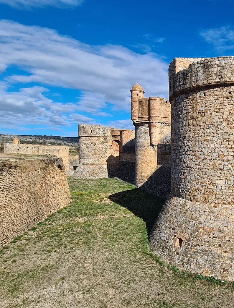 Forteresse de Salses, en pierre avec ses tours et ses remparts sous ciel bleu.