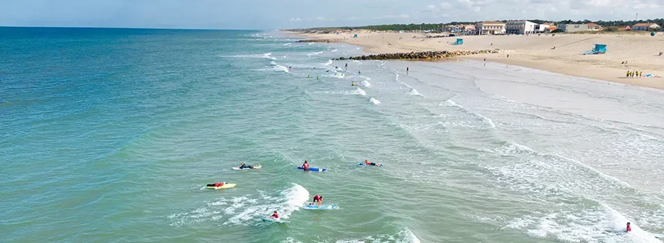 Surfeurs dans les vagues à Montalivet-les-Bains, spot de surf près d'un Camping Club MS Vacances.