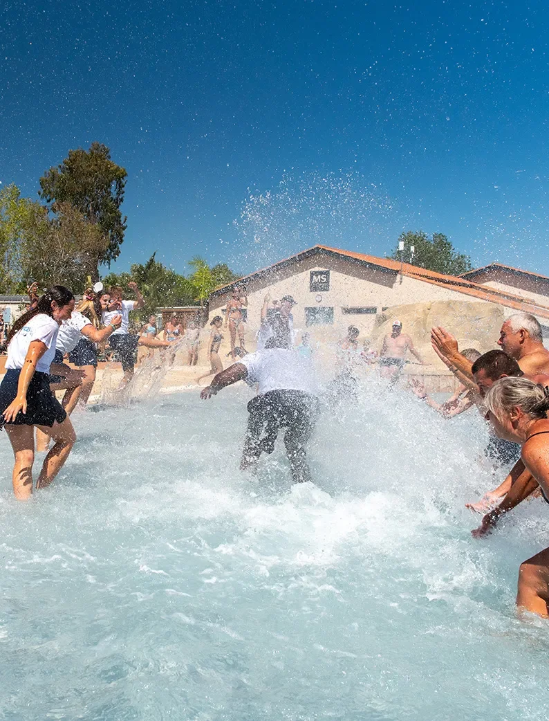 Un groupe d’adultes éclaboussant les animateurs du camping dans la piscine du Camping Club Les Tamaris cinq étoiles.