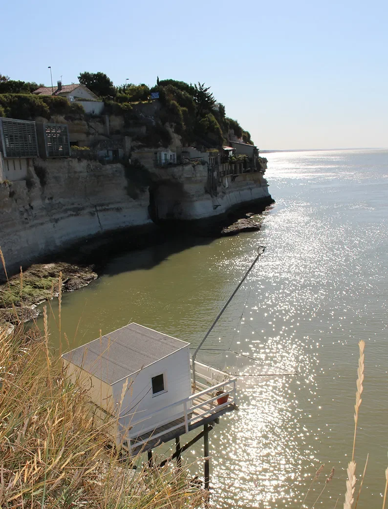 Carrelet de pêche sur pilotis au pied des falaises avec vue sur les grottes troglodytiques de Meschers-sur-Gironde.