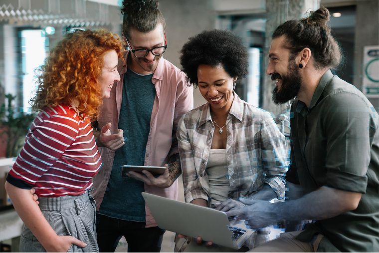 Four people standing around a laptop