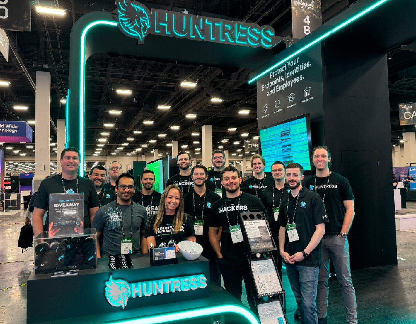 Picture of a group of Huntress employees in front of a Huntress booth at an event