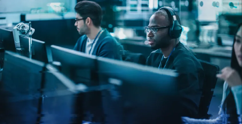 Three people sitting behind computer monitors in an office