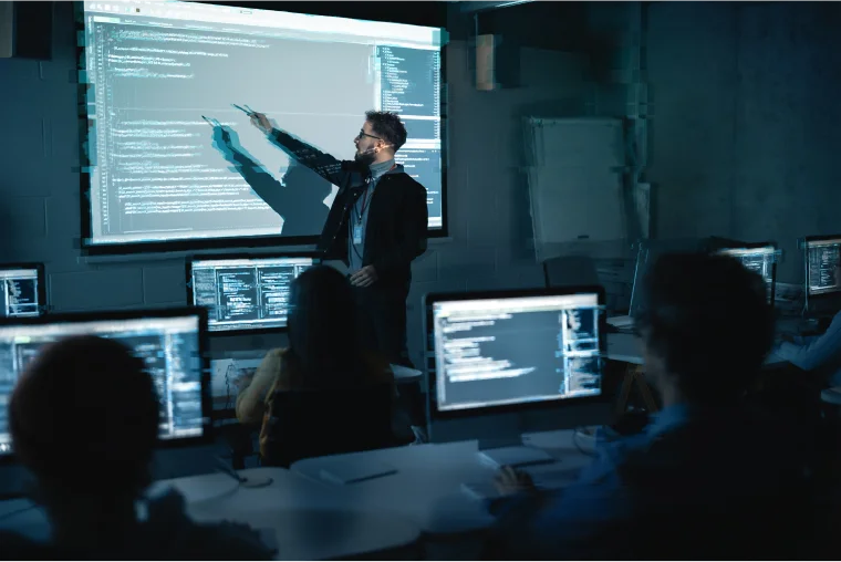 Man in a classroom pointing at the projection screen