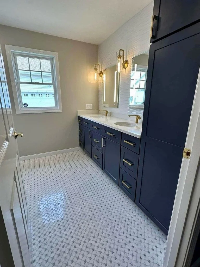 Finished bathroom with navy cabinetry, double vanity and hexagon tile floor