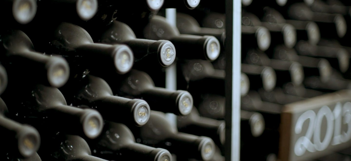 Black, dusty wine bottles stacked in shelves.