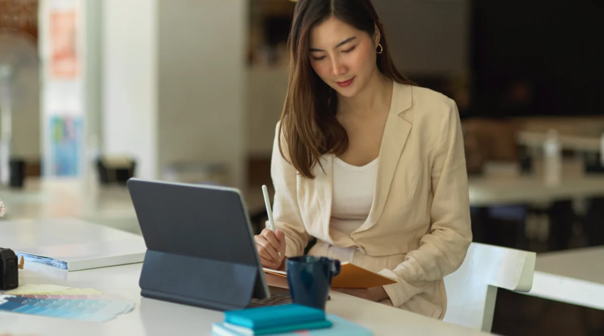Woman in blazer writing with tablet at table