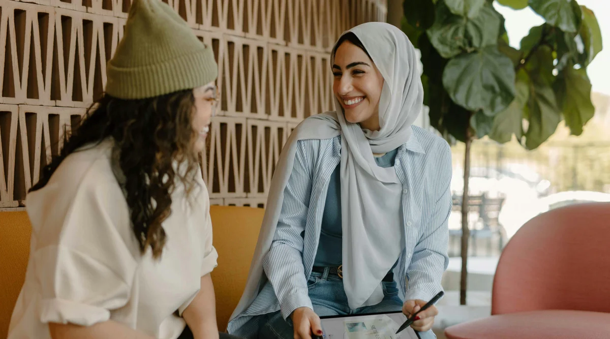 Two women smiling and chatting with a tablet