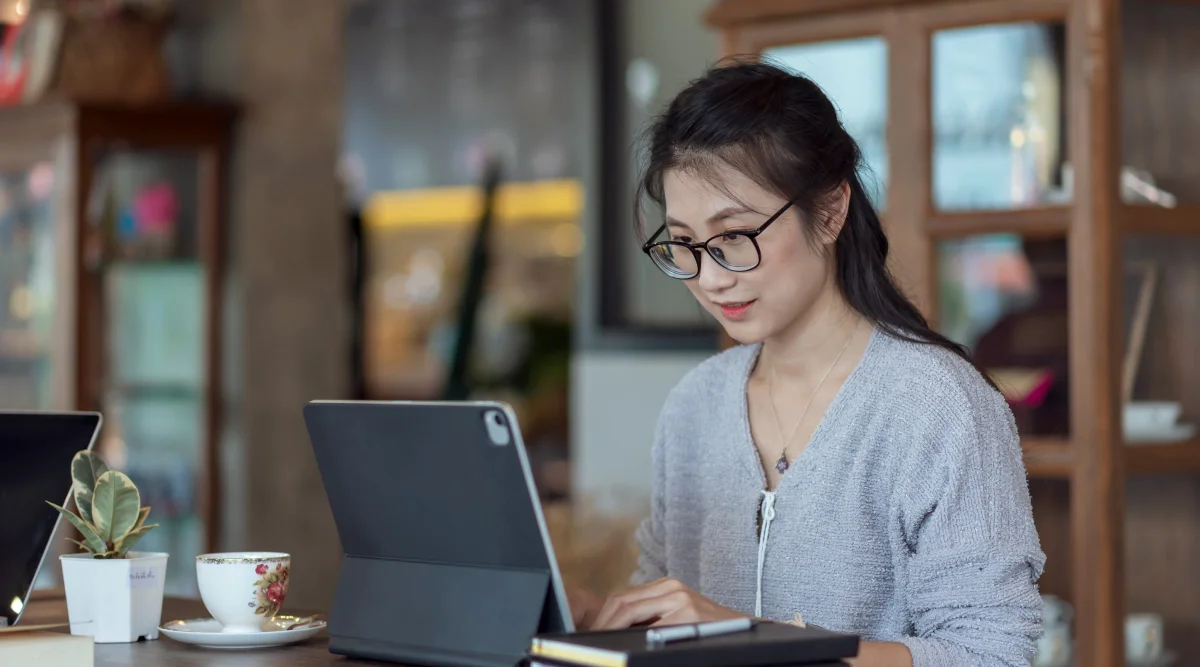 A woman sits at a desk and types on her laptop
