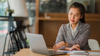 Woman in blazer using laptop at desk