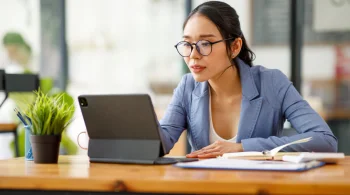 Woman in glasses working on tablet at desk