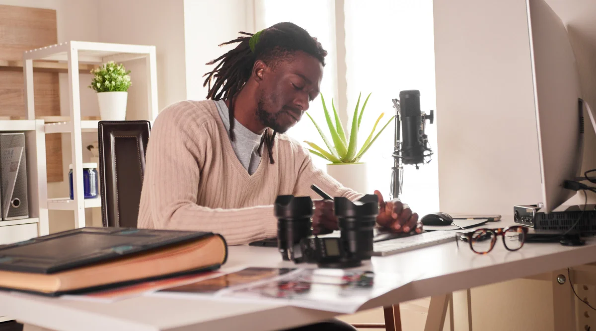 Man writing notes at a desk with camera equipment