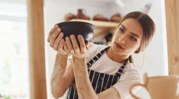 Woman inspecting a clay bowl in a pottery studio