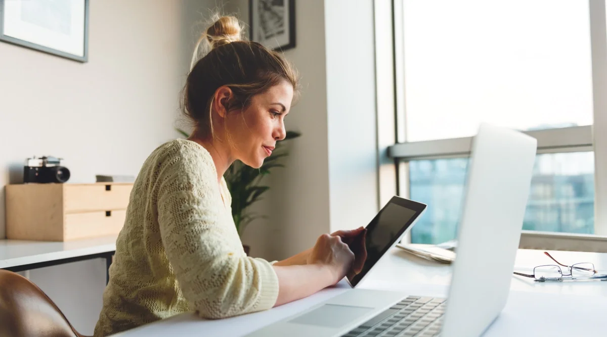 Woman using a tablet at a bright home office desk